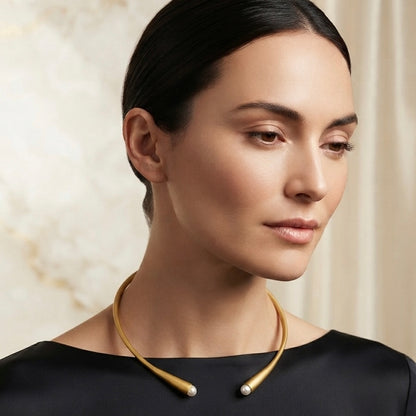 Woman wearing a gold collar necklace with pearl end accents
