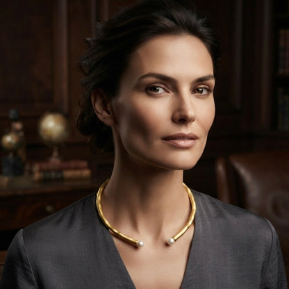 Woman wearing a gold collar necklace with pearl end accents.