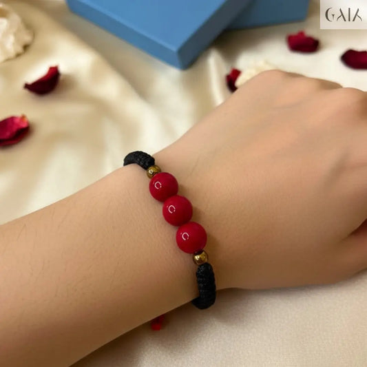 Bracelet with red and black beads on a wrist, with a blue box labeled 'GAL' in the background.
