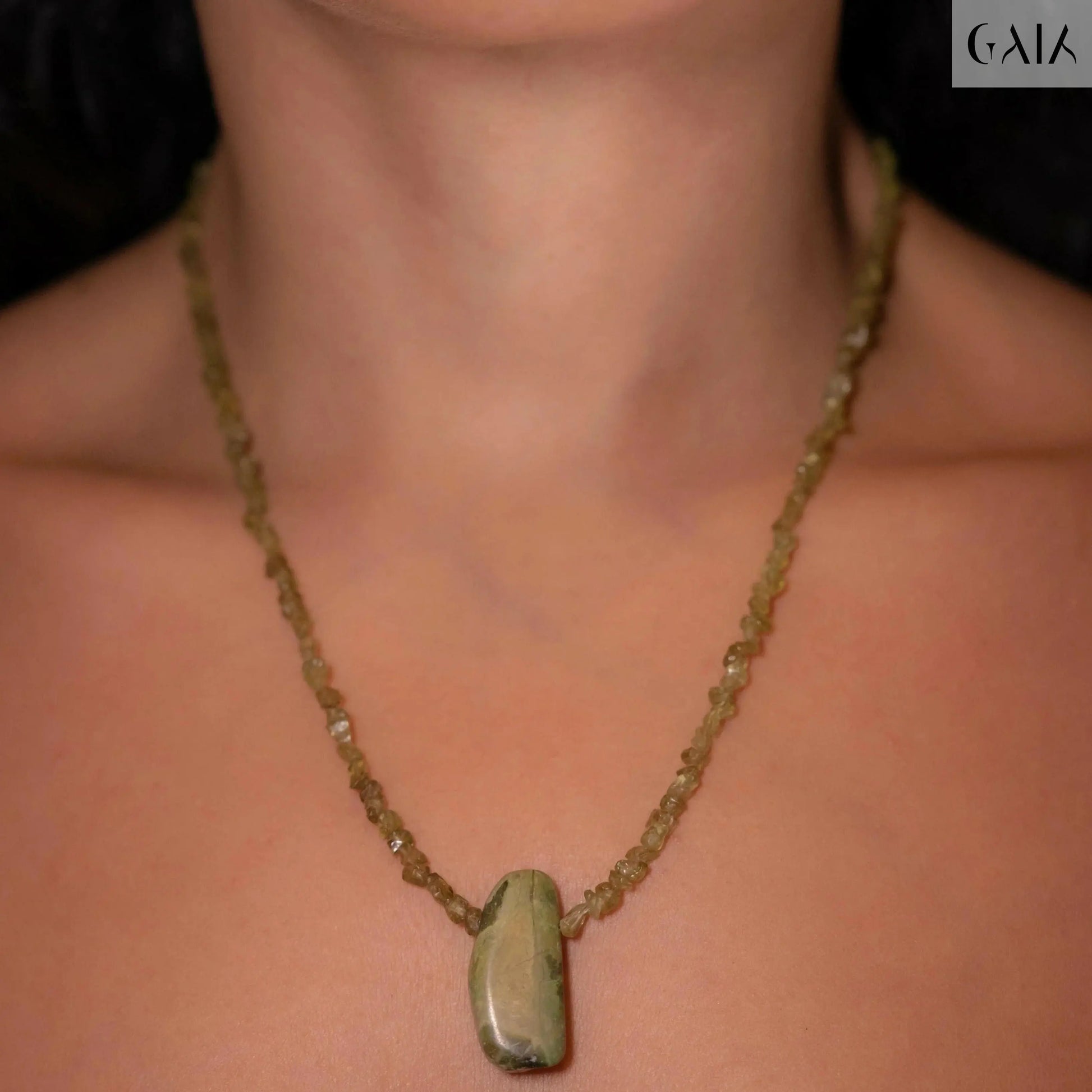 Close-up of a semi-long Hope Necklace featuring green Peridot beads and a natural Tourmaline centerpiece on a neck.