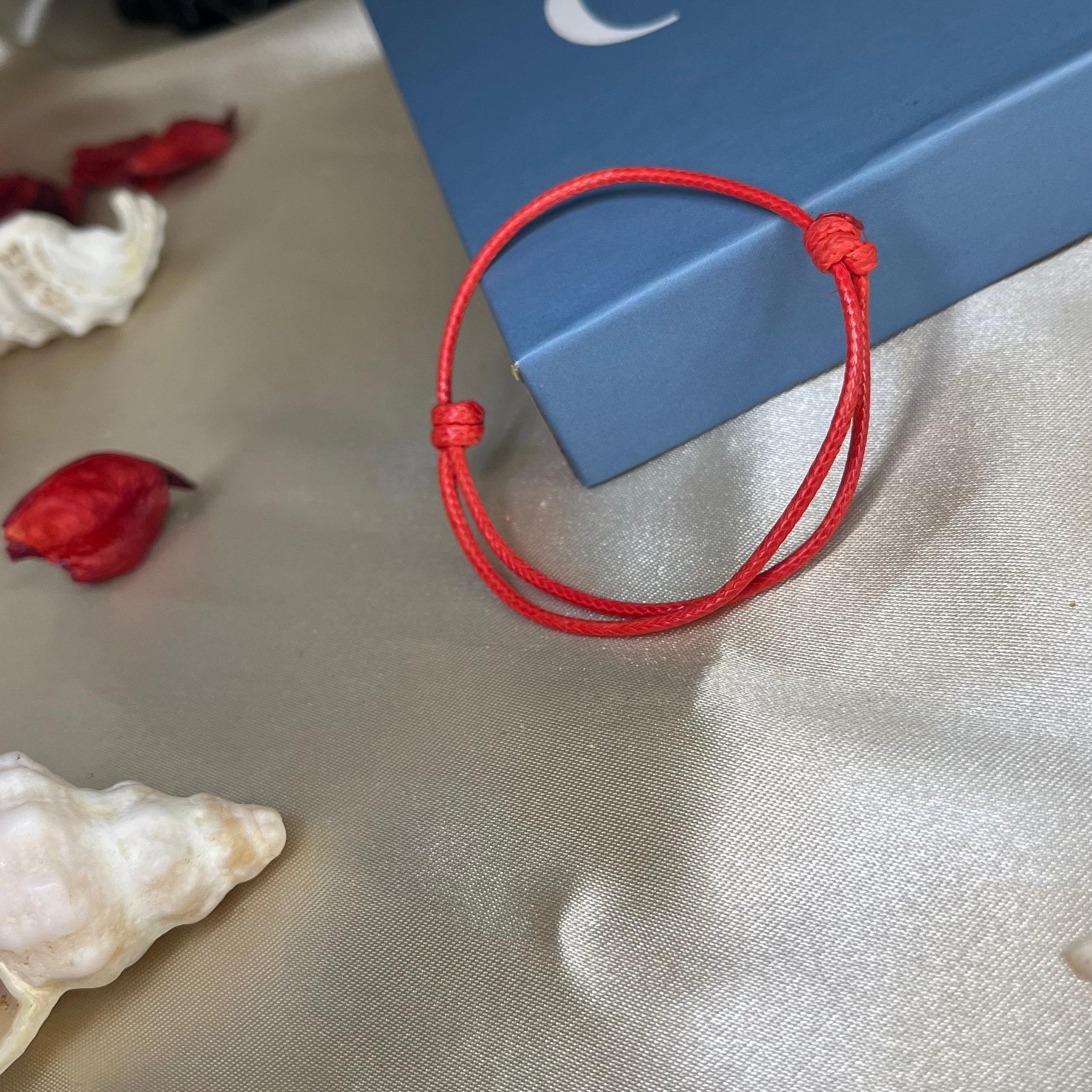 Red bracelet on a light fabric surface with a blue box featuring 'GAIA' branding.