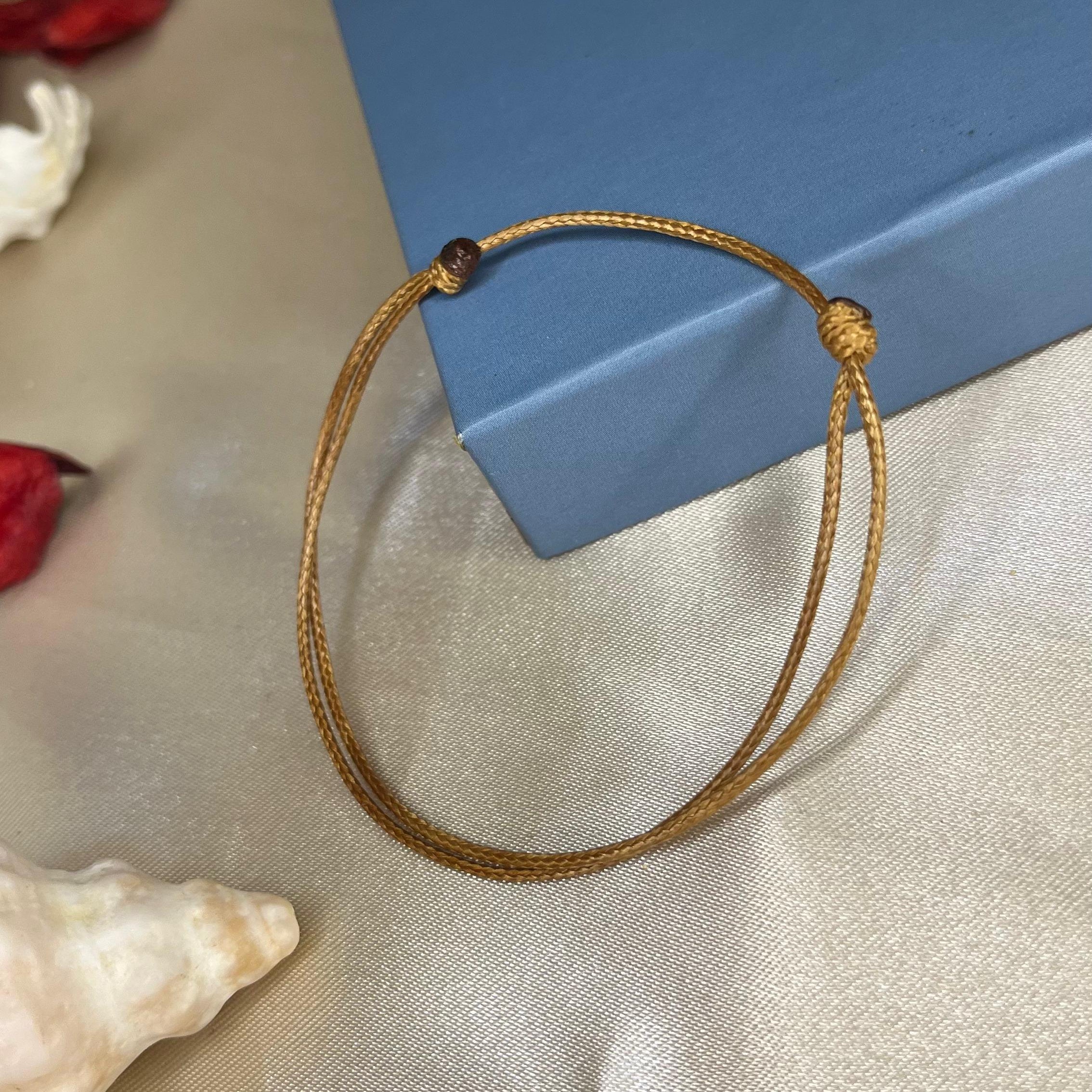Gold bracelet on a light fabric surface with a blue box in the background
