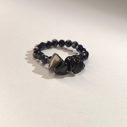 Black beaded bracelet with a heart-shaped stone on a light beige background