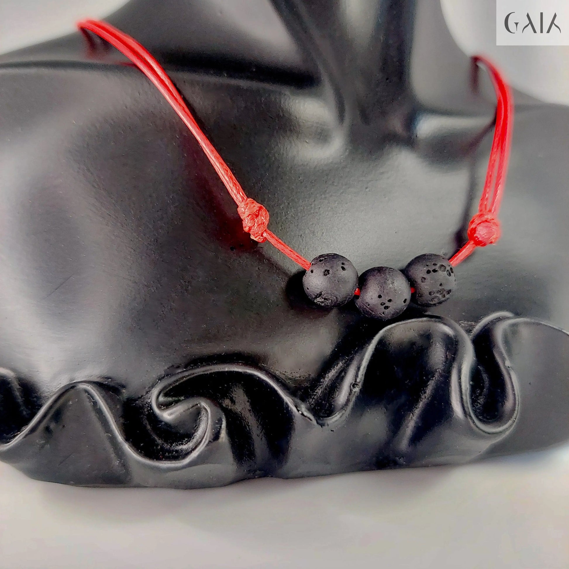 Black beaded necklace with red cord on a black mannequin bust.