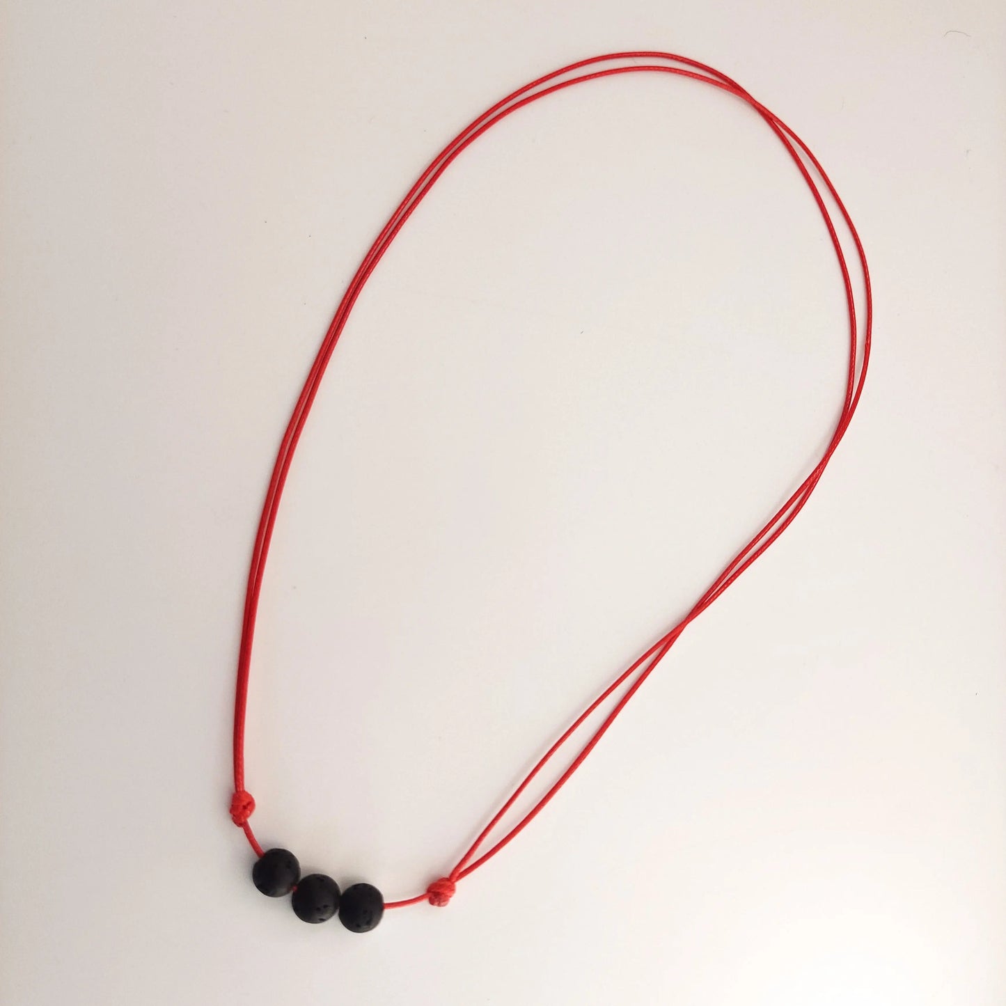 Red necklace with black beads on a white background