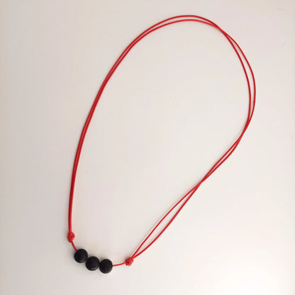 Red necklace with black beads on a white background