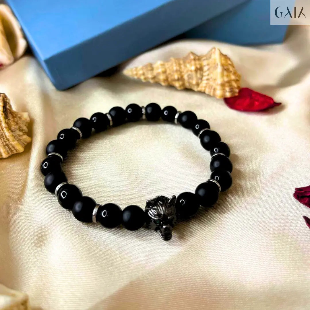 Black beaded bracelet on a beige fabric background with a blue box labeled 'YOK'.