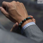Hand wearing a beaded bracelet with a blurred background