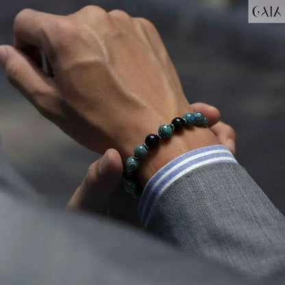 Hand wearing a beaded bracelet with a blurred background