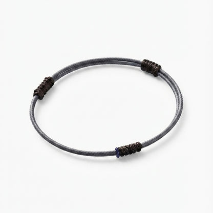 Minimal grey cord bracelet with dark wrapped knot details.
