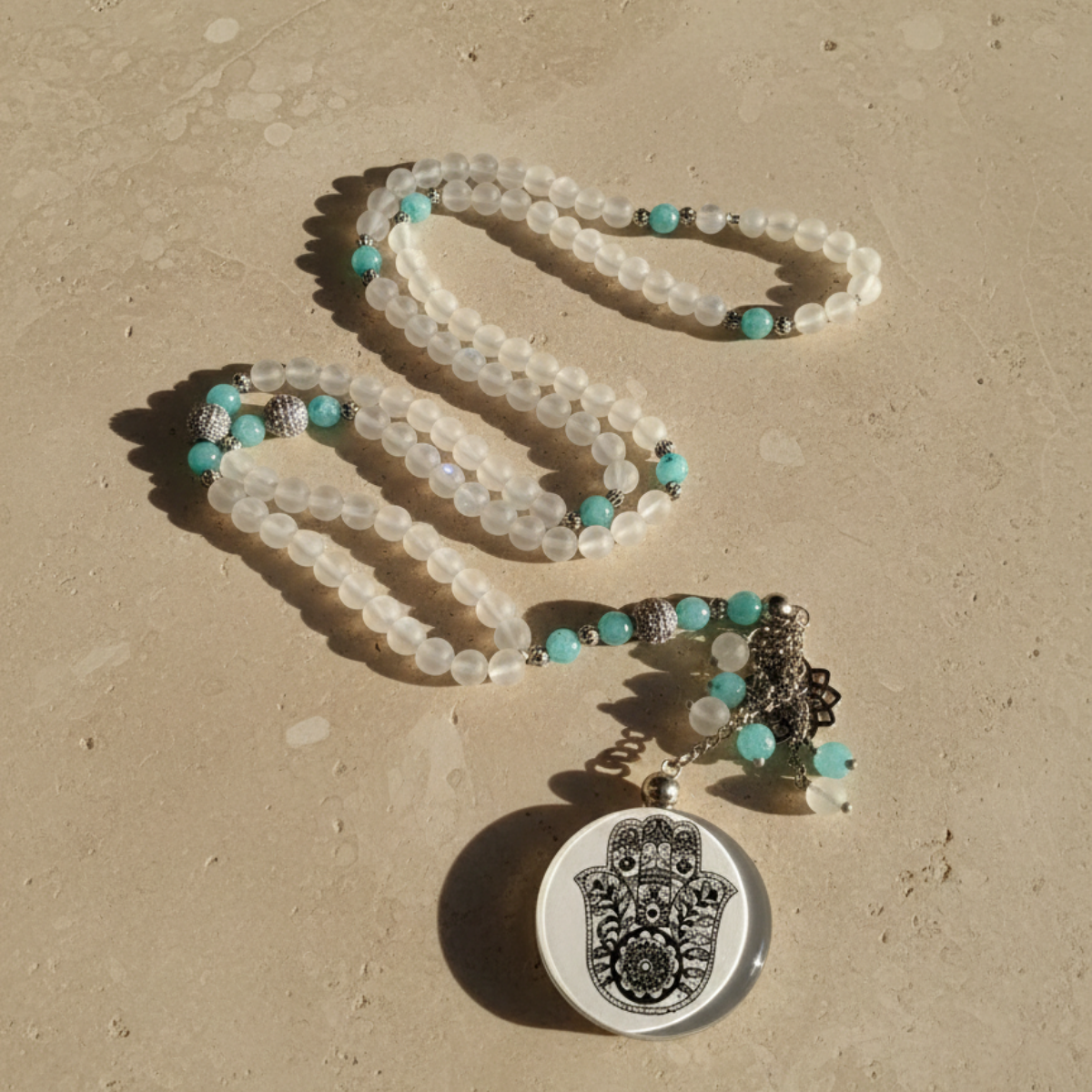 Beaded necklace with a Hamsa pendant on a beige surface