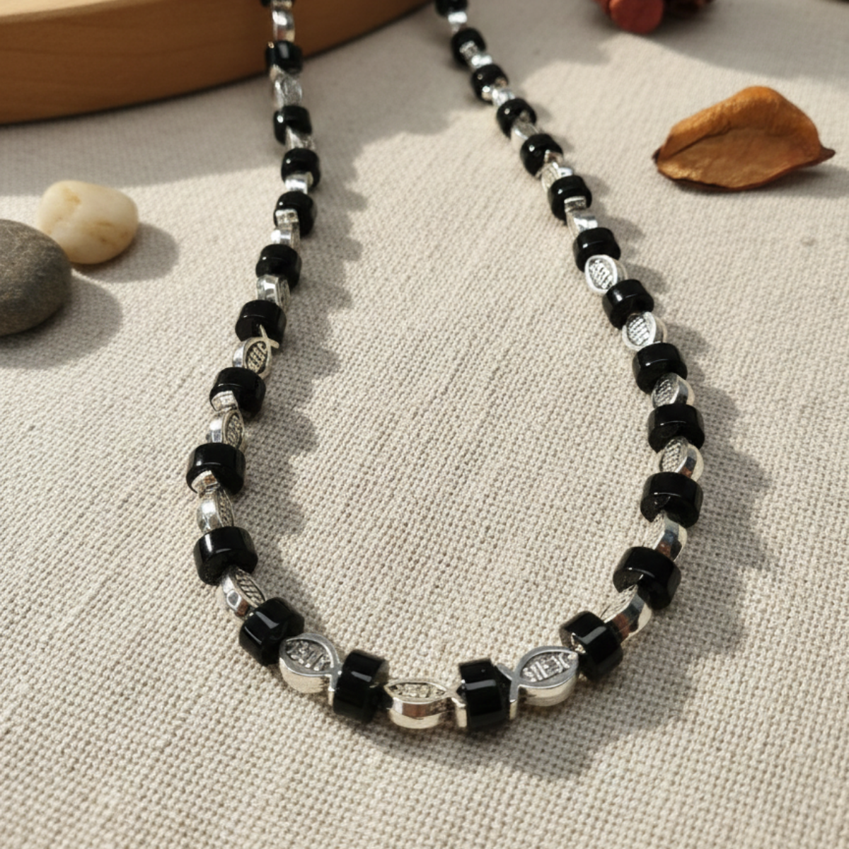 Necklace with black and silver beads on a textured surface