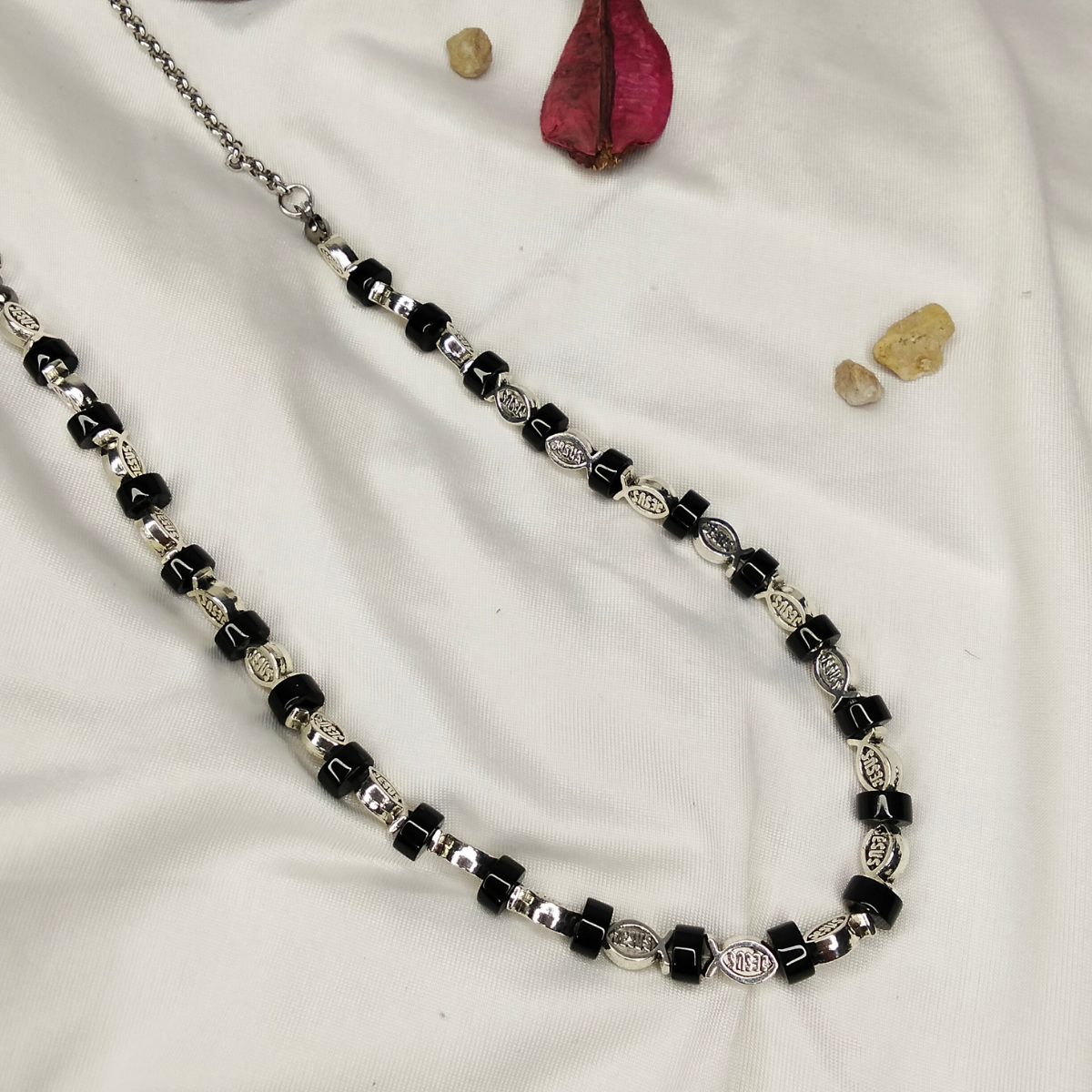 Necklace with black and silver beads on a white fabric background