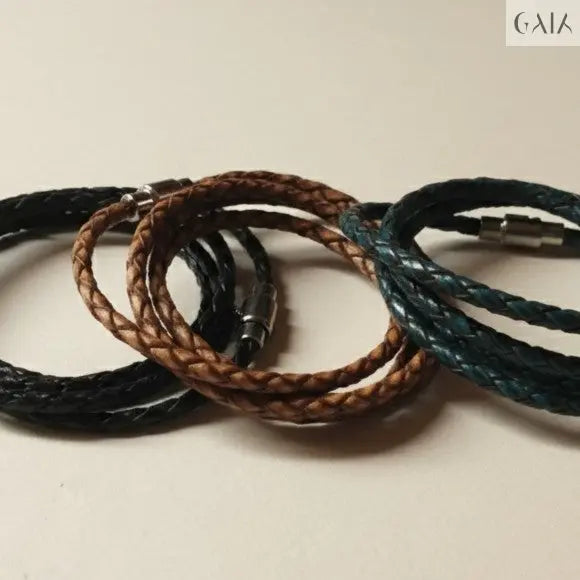 Three braided leather bracelets in black, brown, and blue on a beige background