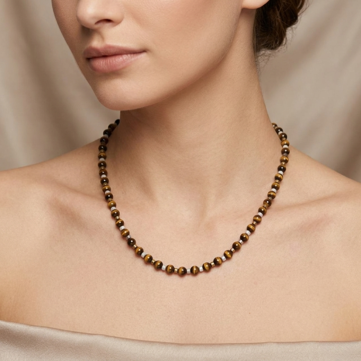 Necklace with brown beads worn by a person against a neutral background