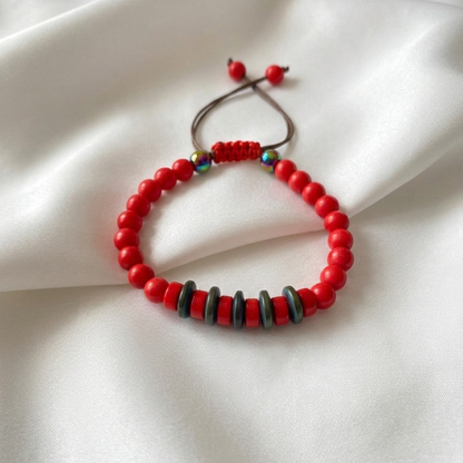 Red beaded bracelet with black and multicolor beads on a white fabric background