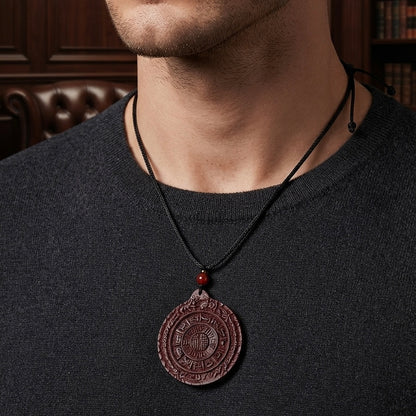 Man wearing a red carved medallion pendant necklace on a black cord.