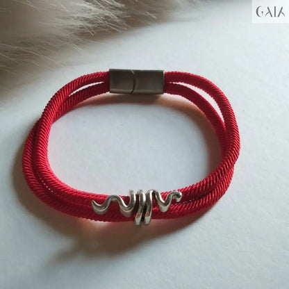 Red braided bracelet with a silver clasp on a light background