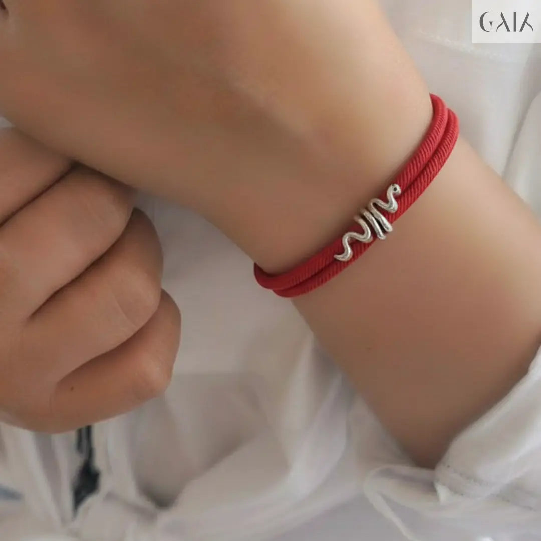 Red bracelet with silver design on a wrist against a white background