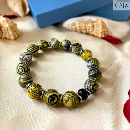 Beaded bracelet with yellow and black pattern on a beige surface, with a blue box labeled 'Cala' in the background.