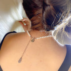 Pearl necklace with a silver chain and pendant on a person's neck.