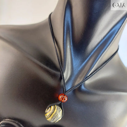 Necklace with a gold and silver pendant on a black satin background

