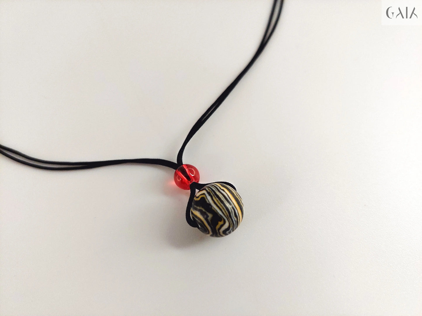 Necklace with a black and white striped pendant on a light gray background

