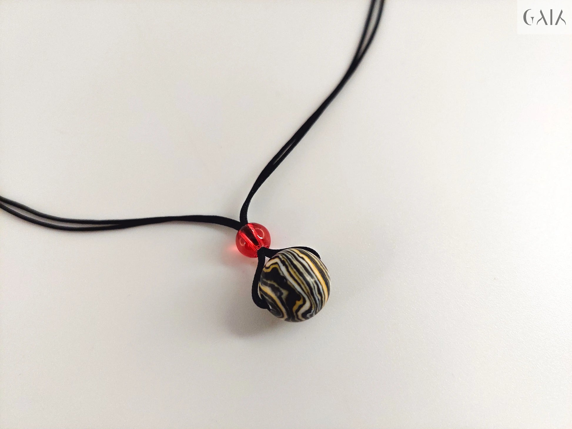 Necklace with a black and white striped pendant on a light gray background

