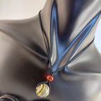 Necklace with a gold and silver pendant on a black satin background

