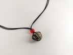 Necklace with a black and white striped pendant on a light gray background

