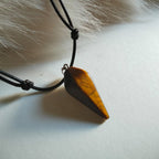 Wooden pendant on a black cord against a fur background