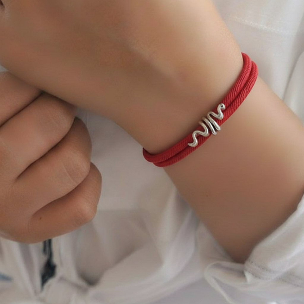 Red bracelet with silver design on a wrist against a white background