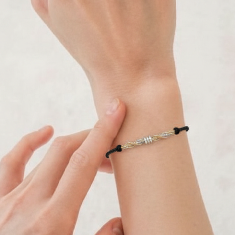 Hand wearing a black and silver bracelet on a light background