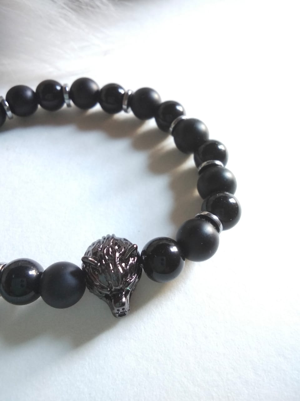 Black beaded bracelet with a lion head charm on a white background